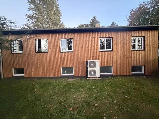 Husets lange træfacade set fra græsplænen