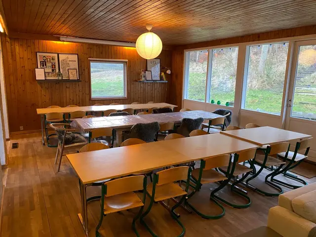 Spisestue med lange borde, stole og store vinduer