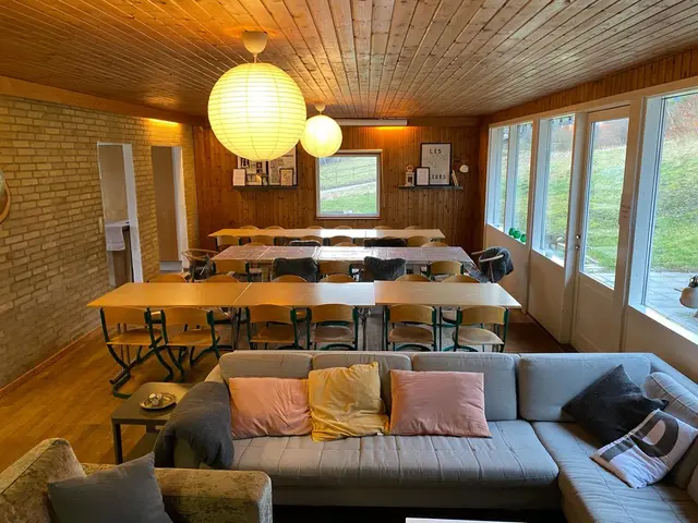 Spisestue med lange borde, stole og sofaer