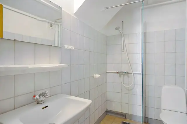 Lyst badeværelse med håndvask og bruser